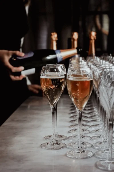 Champagne hälls upp i rad av glas under minglet.